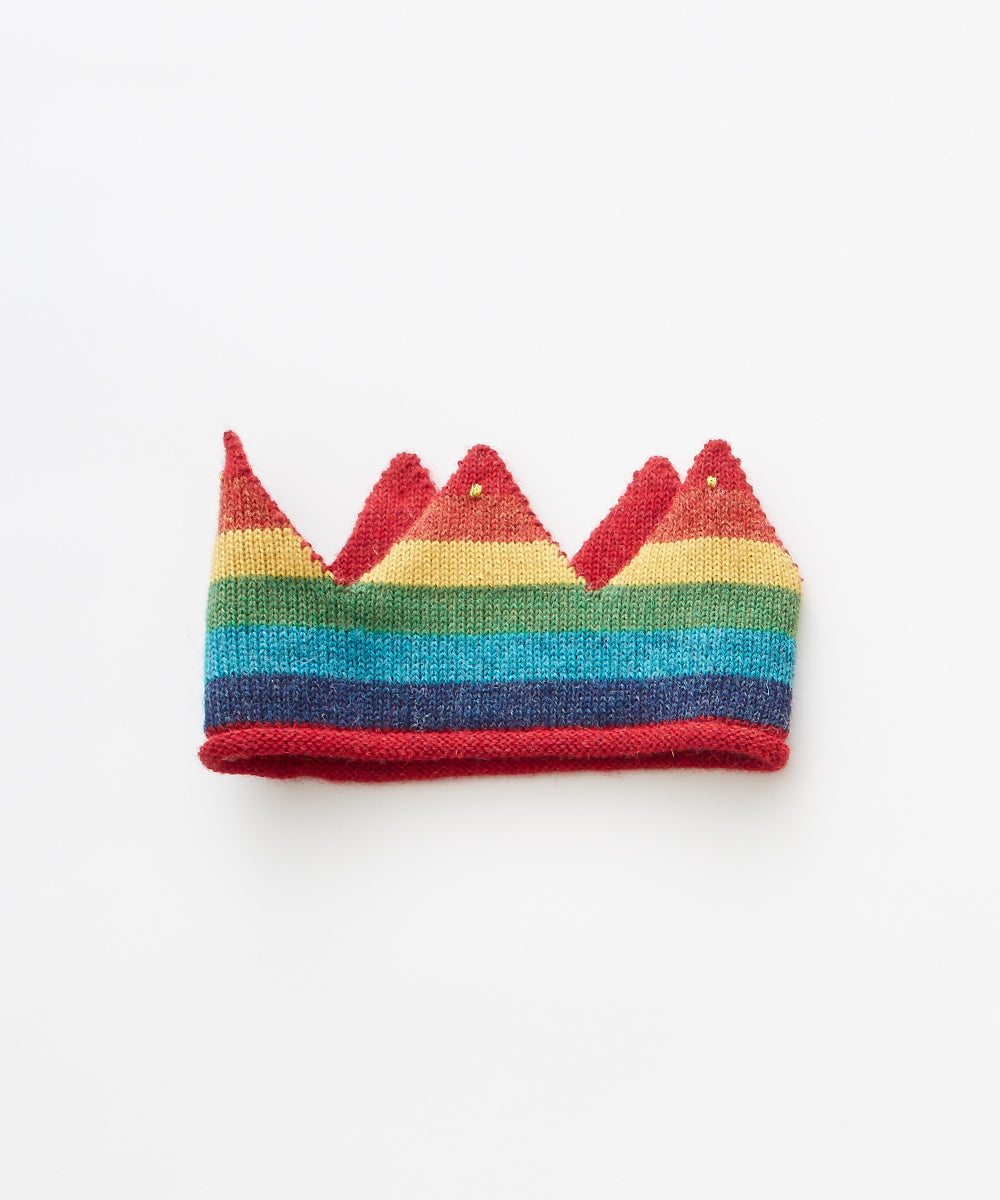 The Rainbow Crown is a knitted accessory with rainbow stripes, red edges, five points, and small gold beads.