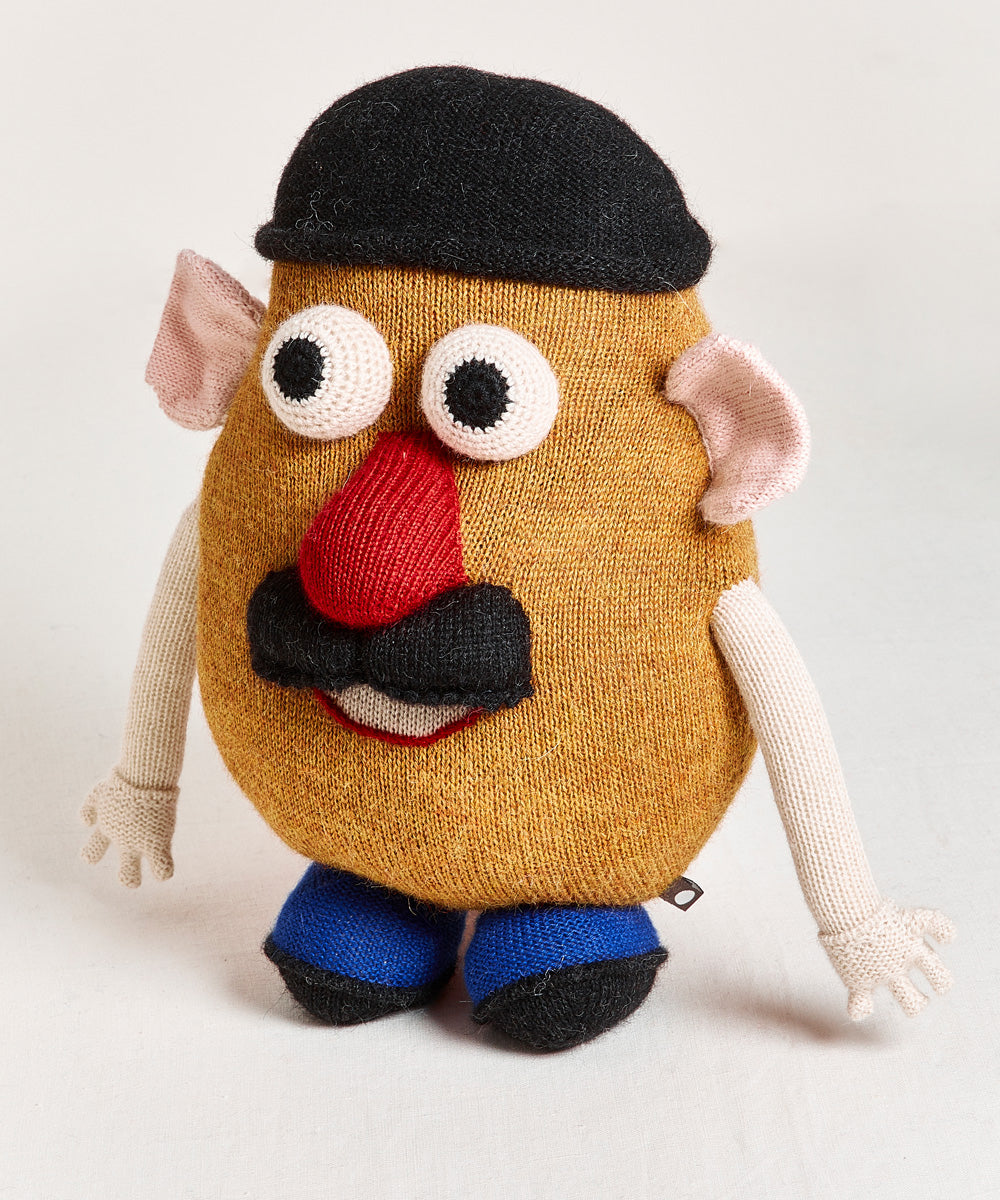 A handmade toy named "Funny Face Pillow," resembling a potato with googly eyes, a red nose, a black hat, a mustache, and blue shoes.