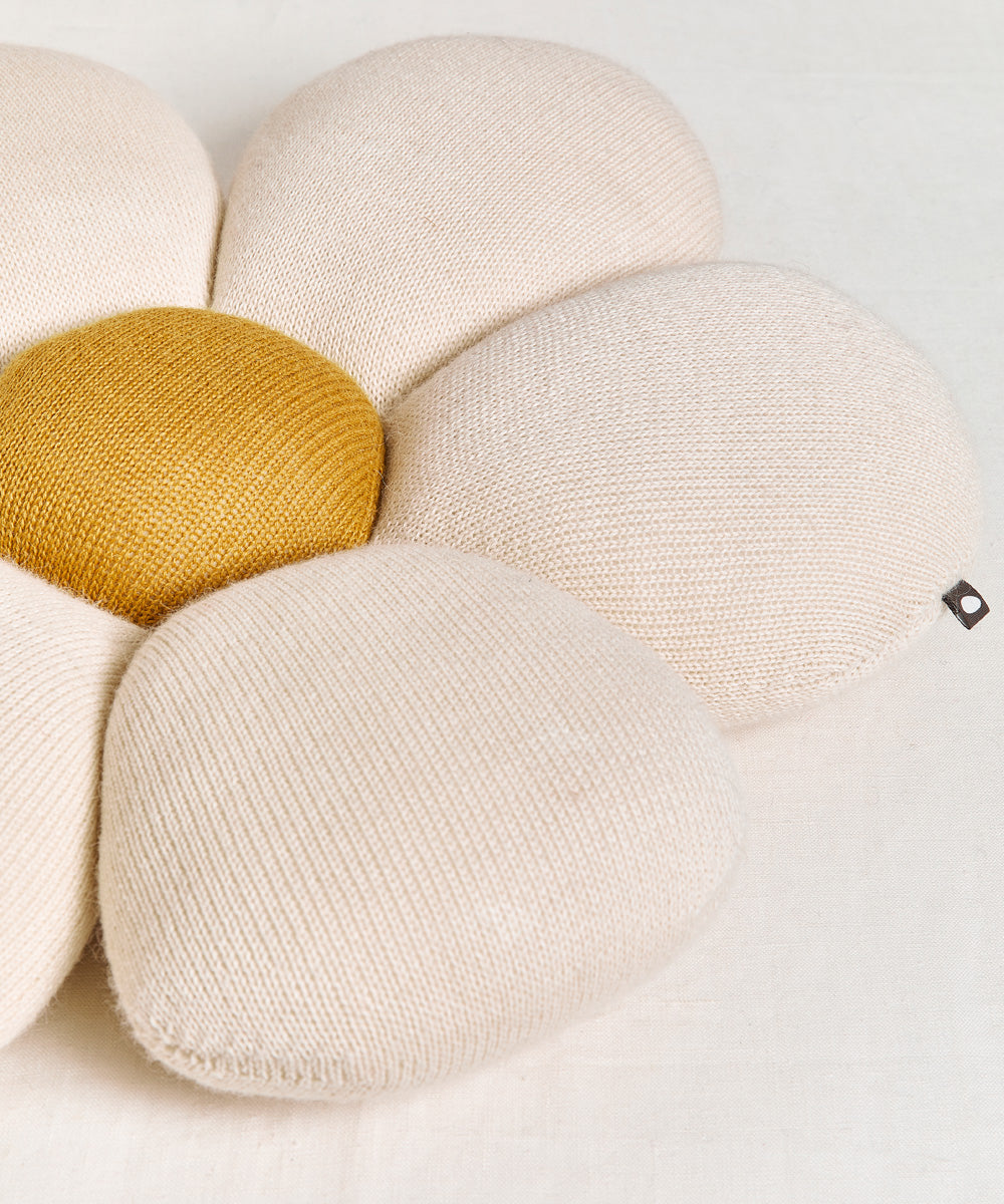 Daisy Pillow: A cream flower-shaped cushion featuring a yellow center on a light fabric background.
