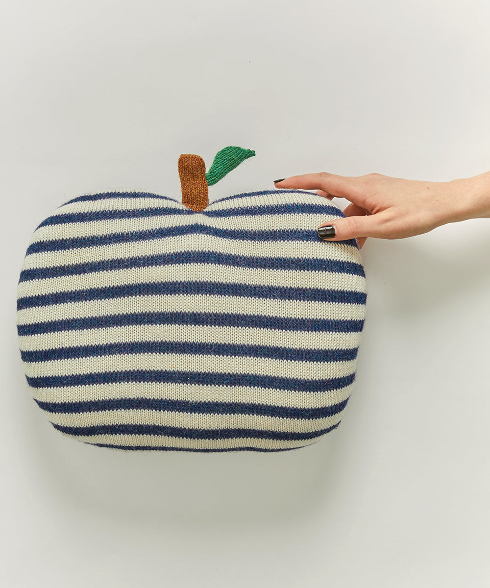 Hand touching the Apple Pillow, featuring blue and white stripes with a green leaf and brown stem.