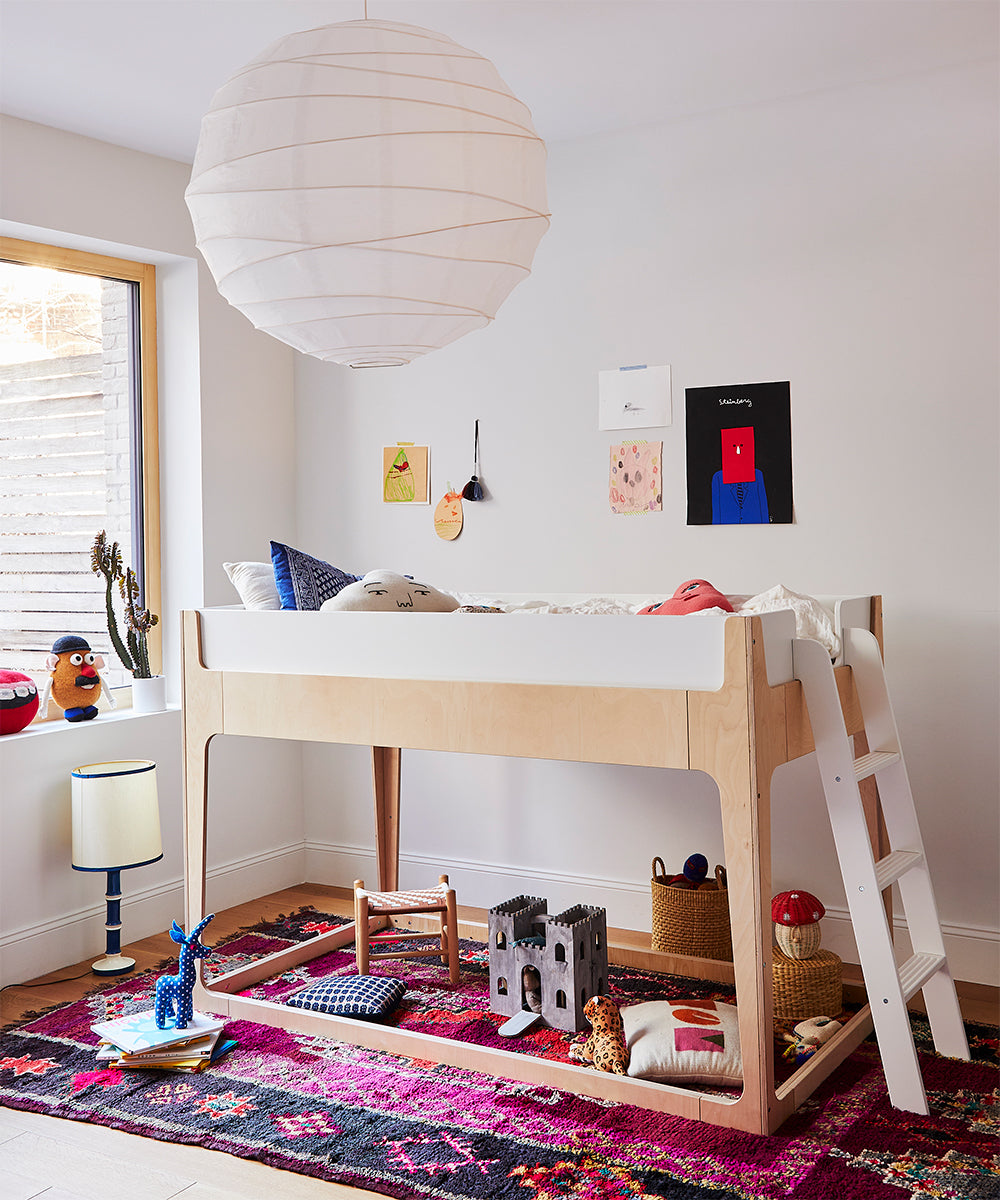 A childrens room features the Perch Nest Bed loft with toys underneath and a large paper lantern above. A bright rug and wall art complete the decor.