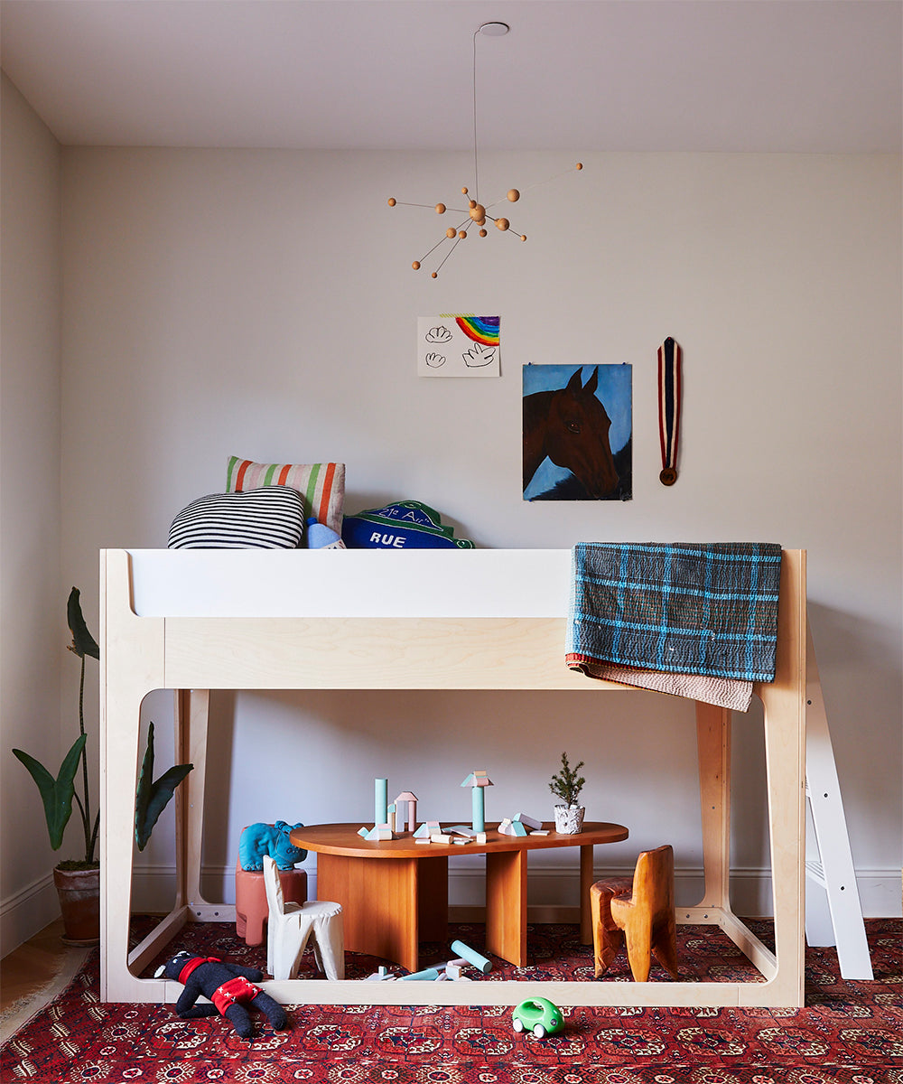 A cozy and colorful kids room with a Perch Nest Bed, toys, a rug, and fun wall decor.