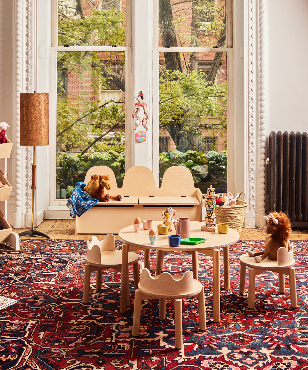 Children's play area with wooden furniture, toys, and a large window.
