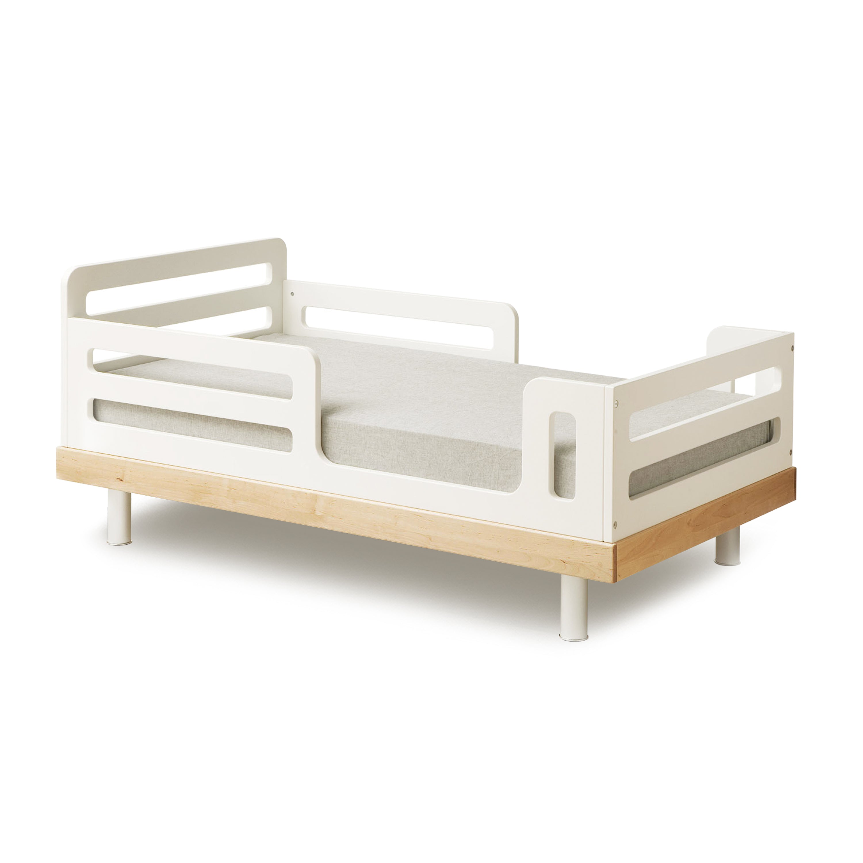 White and wood toddler bed with side railings and a light gray mattress.