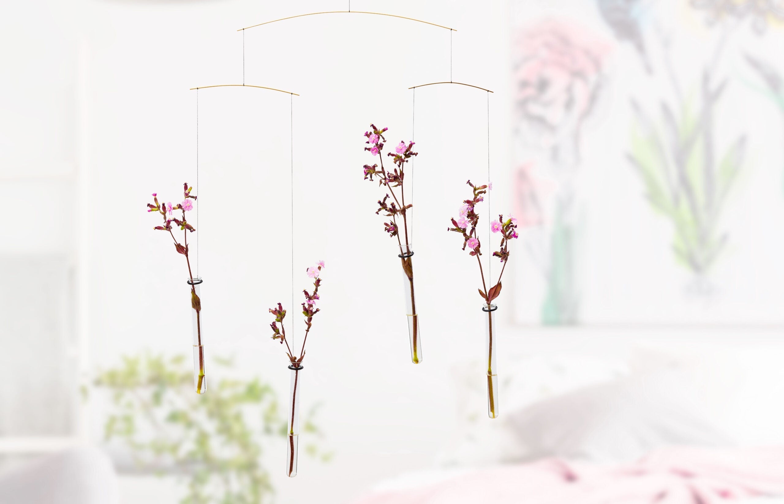 Flying Flowers is a minimalist mobile featuring four hanging glass tubes that hold pink flower branches.