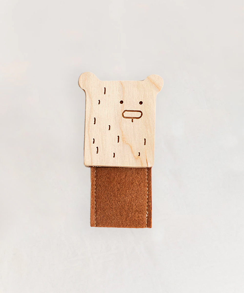 Le Bear Finger Puppet, featuring an engraved wooden bear-shaped clip on top of a brown felt strip, set against a plain background.