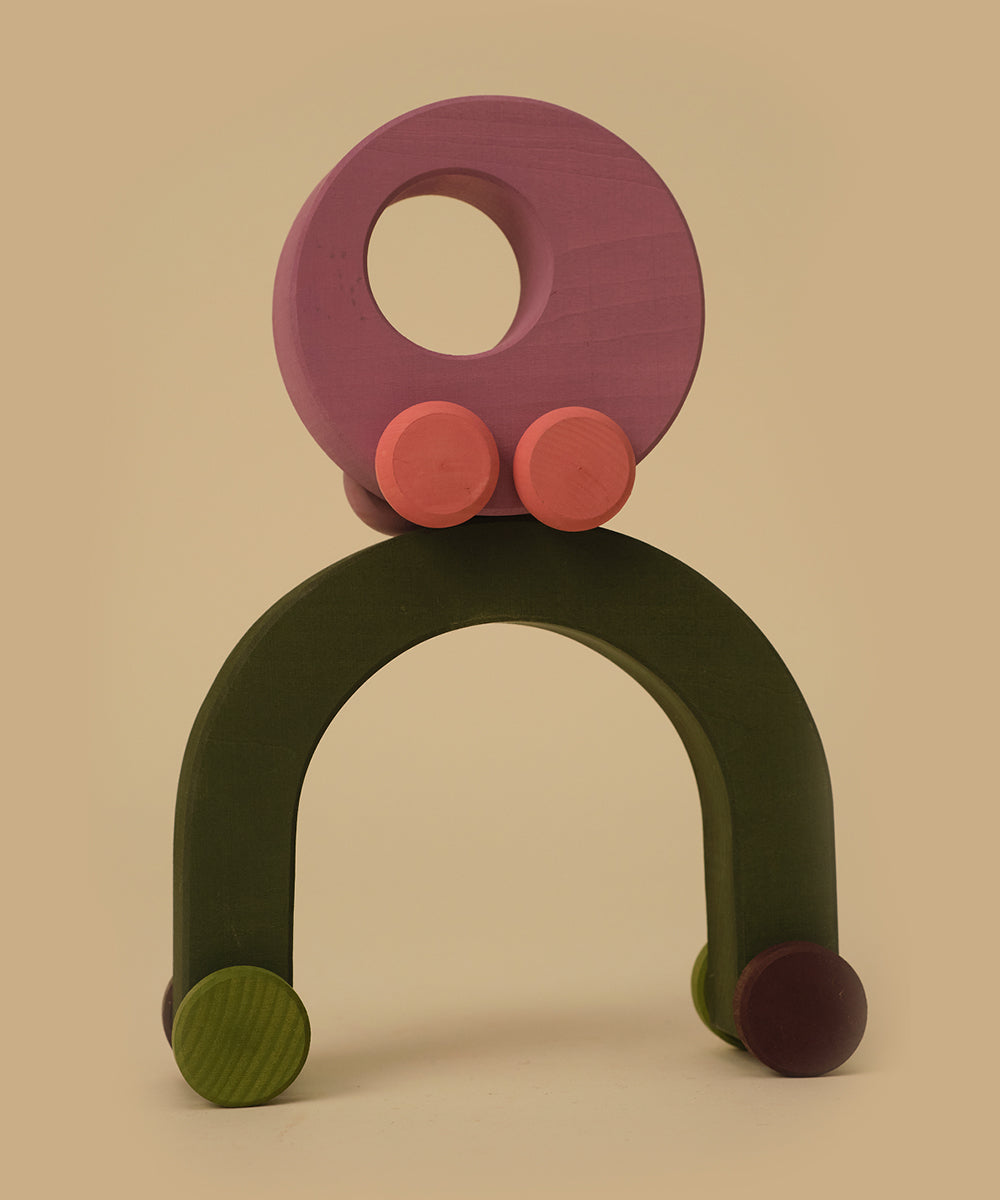 Le Vehicle Duet: wooden arch and circle toys with small colored wheels, neatly stacked on a beige background.