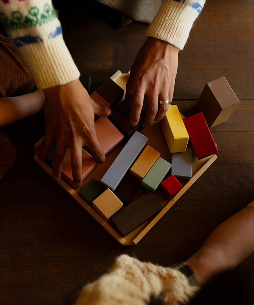 Two people playing with wooden blocks on a wooden table