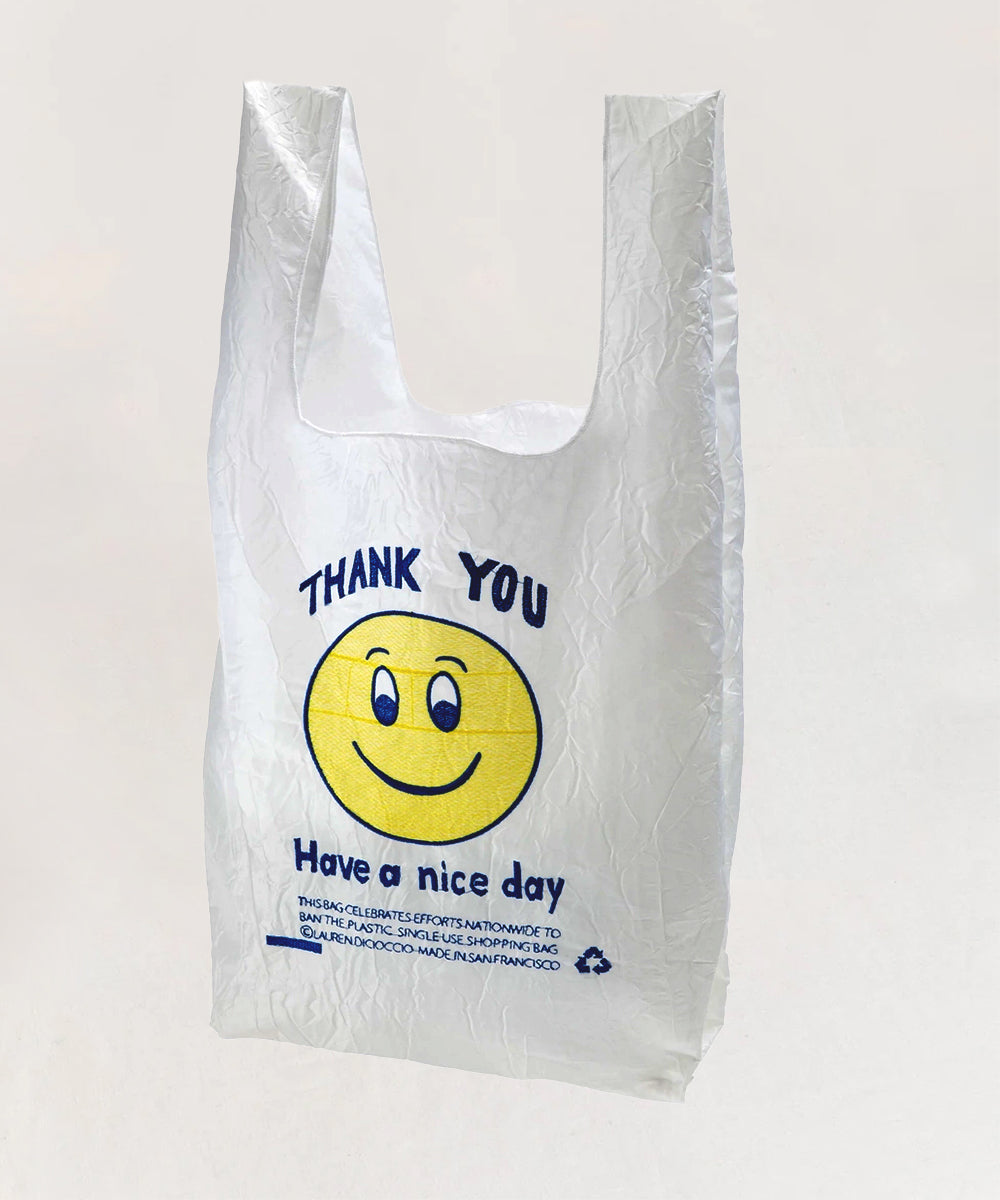 The Le Thank You Tote is a white plastic bag with a yellow smiley face and blue text that says "Thank you, have a nice day.