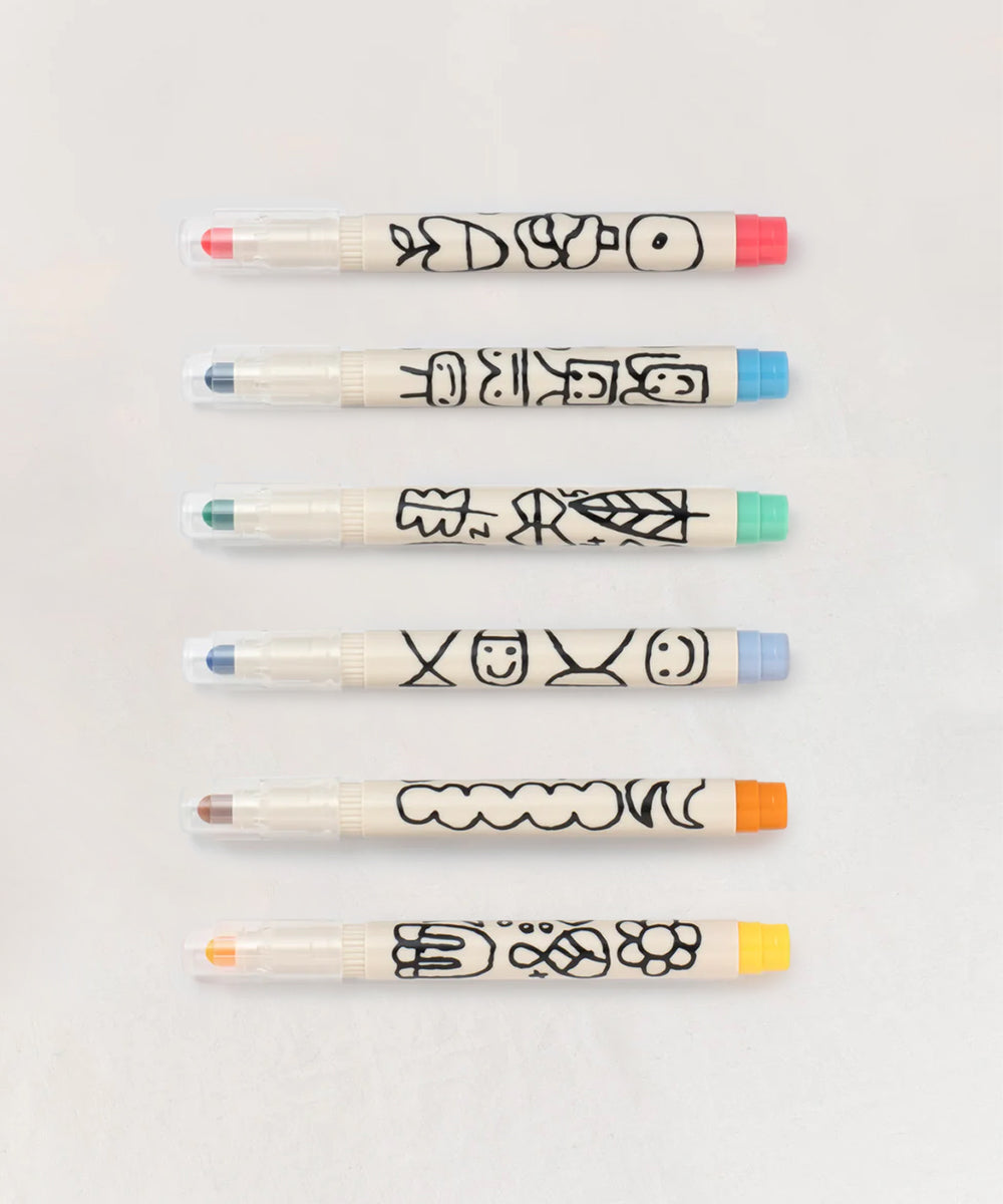 Six Le Well Rounded Markers with colorful caps and playful black doodles, neatly arranged in a row.