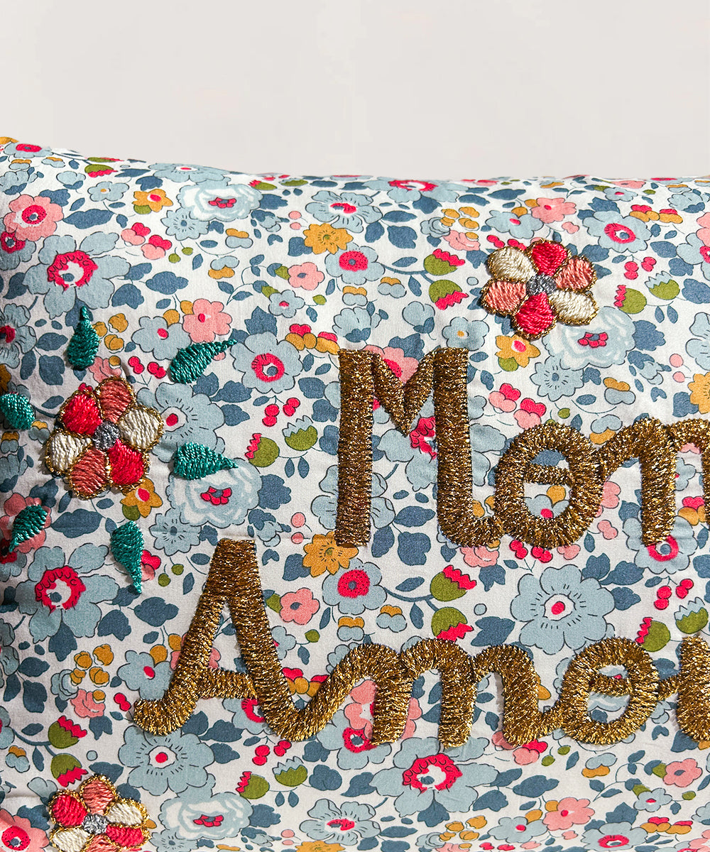 Le Embroidered Pillow - Mon Amour features a vibrant floral pattern with colorful embroidery and "Mon Amour" stitched in gold thread.