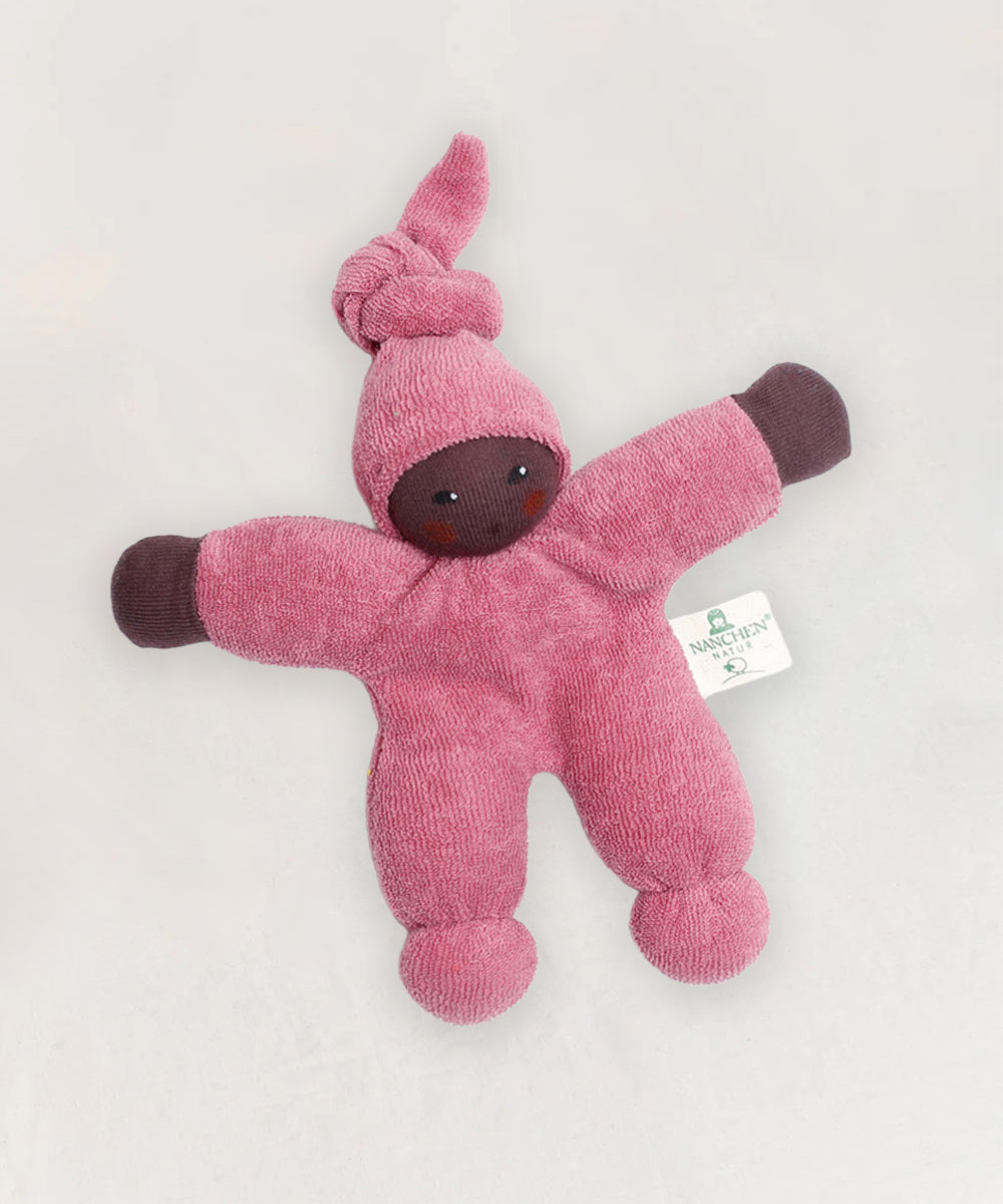 The Waldorf Doll - Pink features a soft pink plush body, knotted hood, and brown face and hands, pictured lying on a light background.