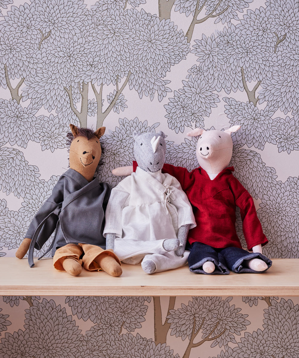 Three stuffed animal toys—a horse, a unicorn, and Le Piggy—sit on a shelf against a floral wallpaper background.