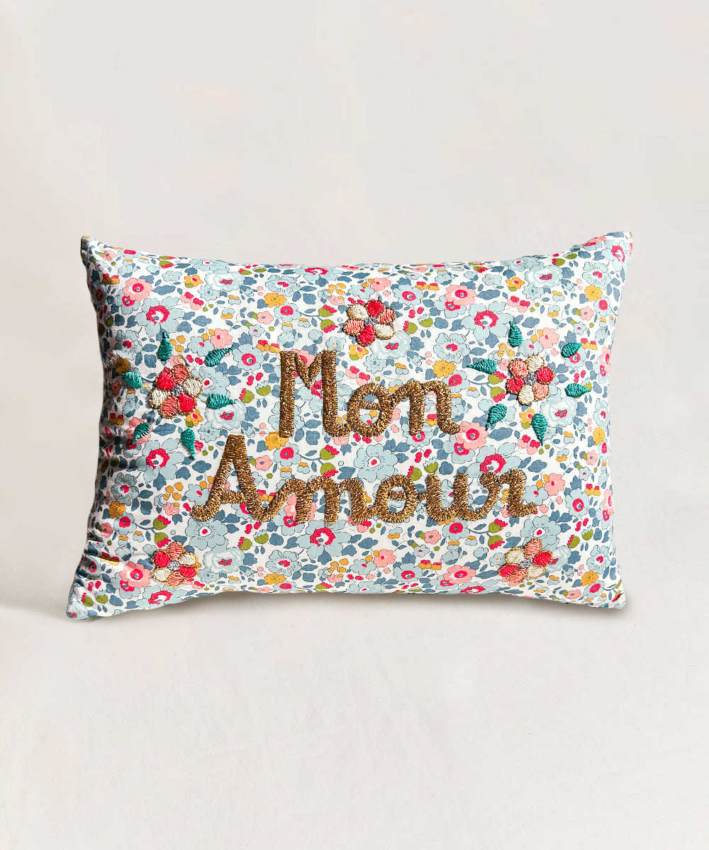 Le Embroidered Pillow - Mon Amour: Rectangular pillow featuring floral design and "Mon Amour" in large gold letters on the front.