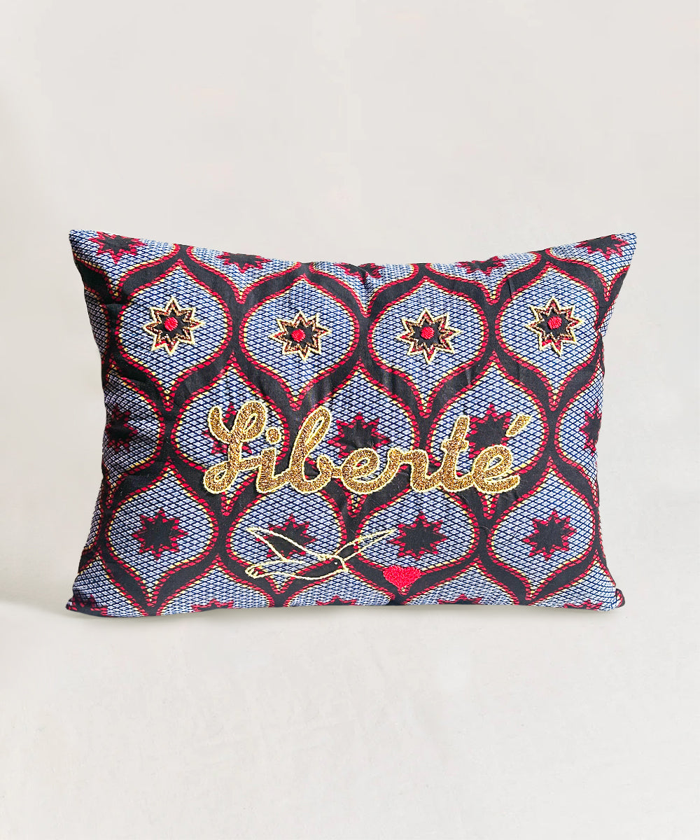 Decorative pillow with geometric pattern and 'Liberte' text on a white background