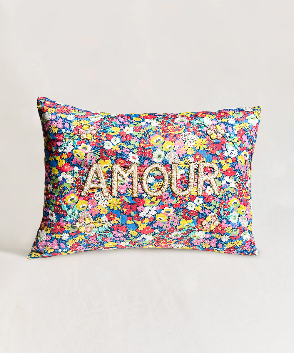 Le Embroidered Pillow - Amour: Rectangular pillow featuring a colorful floral pattern and "AMOUR" embroidered in large letters on the front.