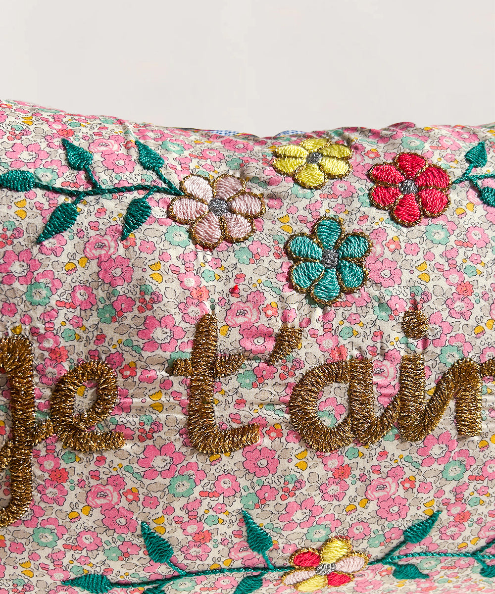 Close-up of Le Embroidered Pillow - Je T'aime, featuring colorful floral embroidery and "je t'aime" in gold thread.