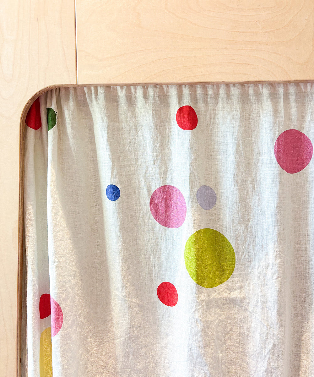 Printed Perch Bunk/Loft Linen Curtains with a colorful polka dot pattern hanging from a wooden bunk bed frame.