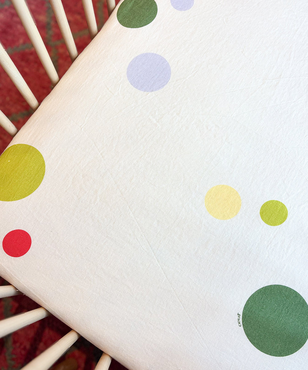 Printed Linen Crib Sheet in off-white with a scattered multicolored polka dot pattern.