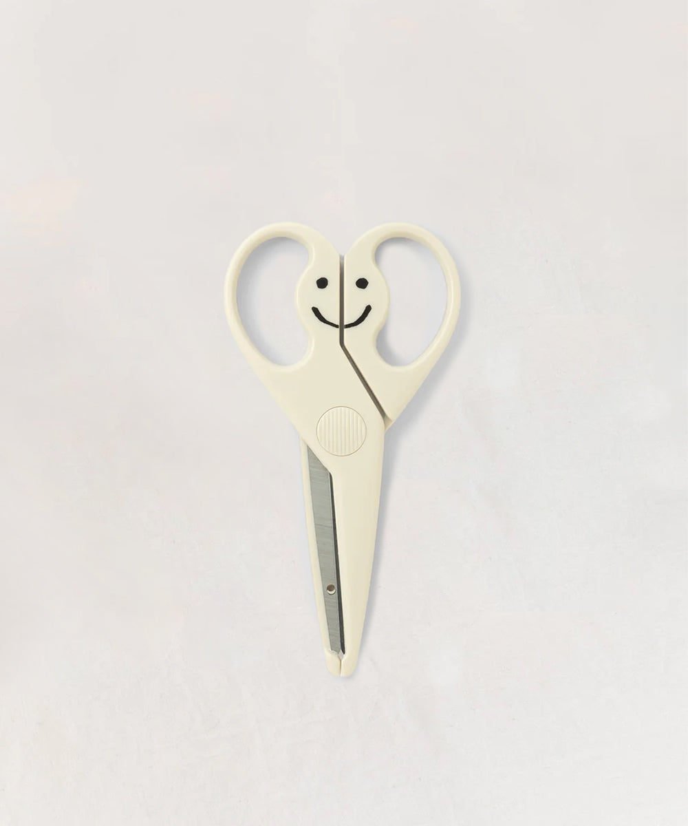 Le Gentle Scissors feature white handles designed as a smiling face, shown on a simple light backdrop.
