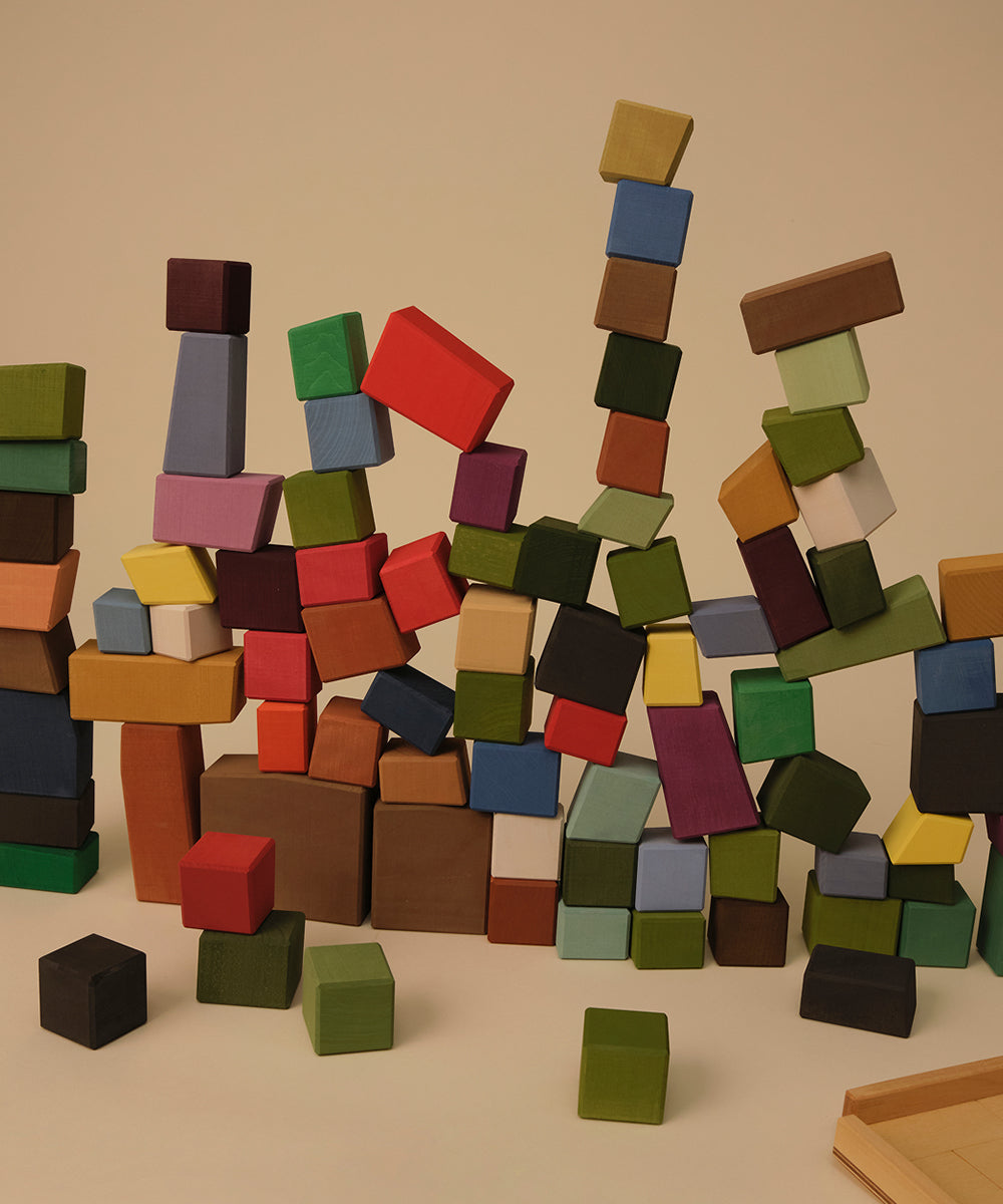 Le Oddy Cubes stacked in tall, uneven towers, their colorful wooden pieces standing out against a neutral background.