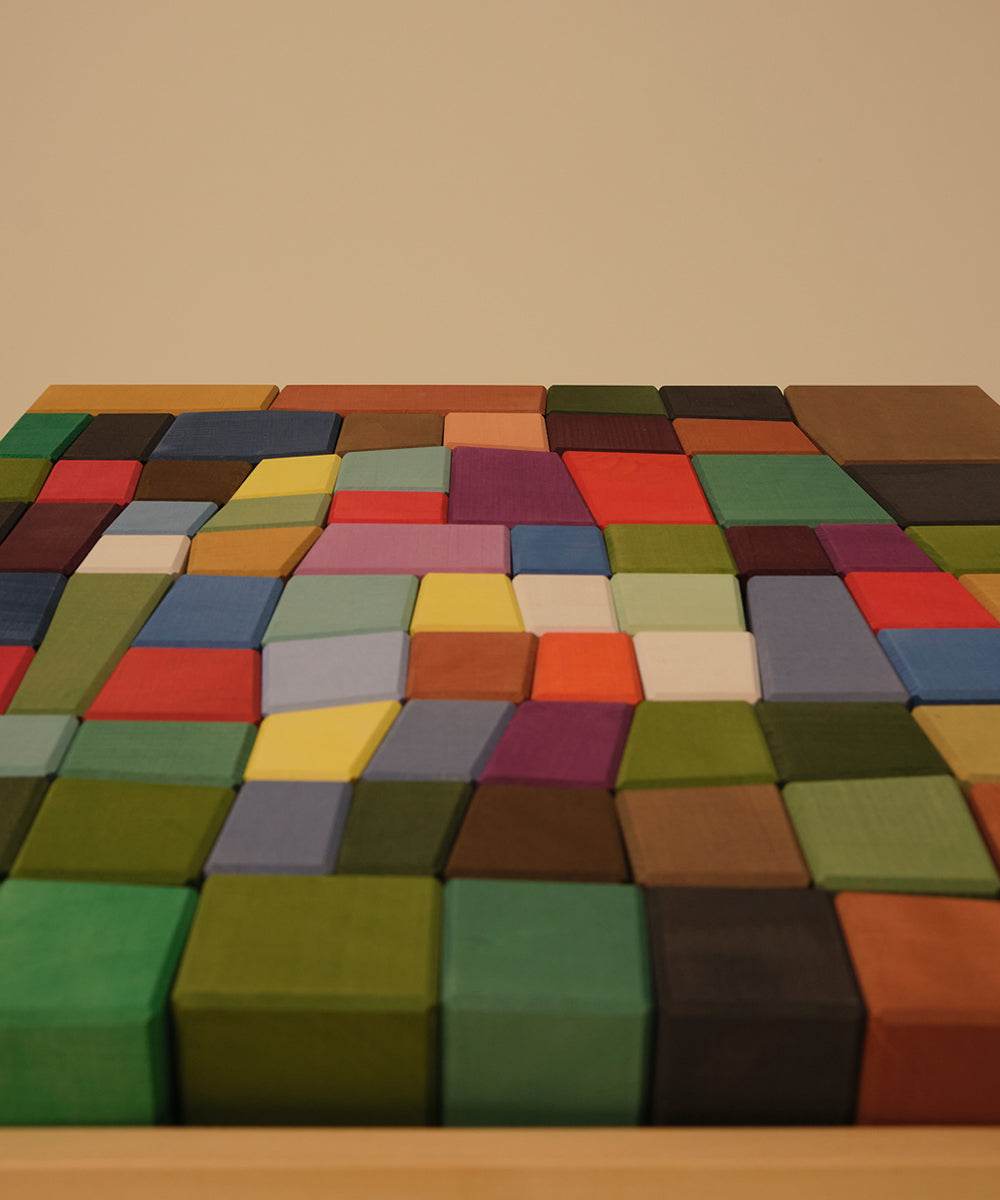Le Oddy Cubes, vibrant fabric-covered rectangles, are arranged in a grid pattern on a beige background.