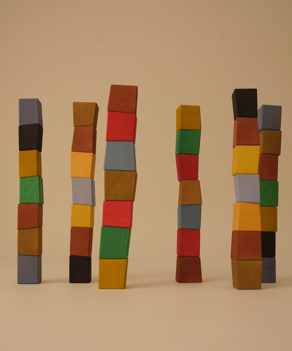 Five uneven stacks of Le Oddy Cubes - Mini in assorted colors standing upright on a beige background.