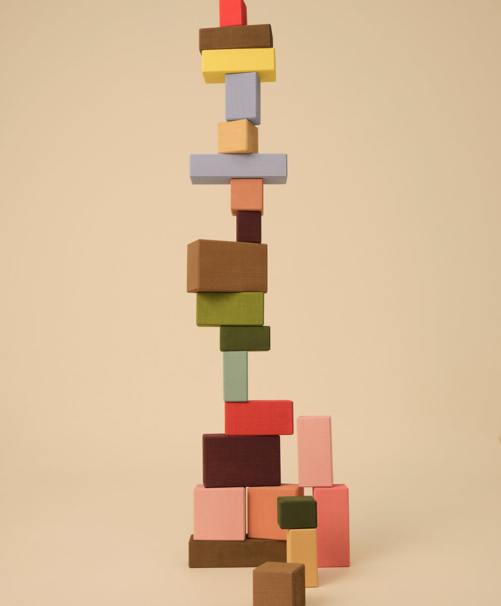A tall, uneven stack of Le Rectangles colorful wooden blocks on a beige background.