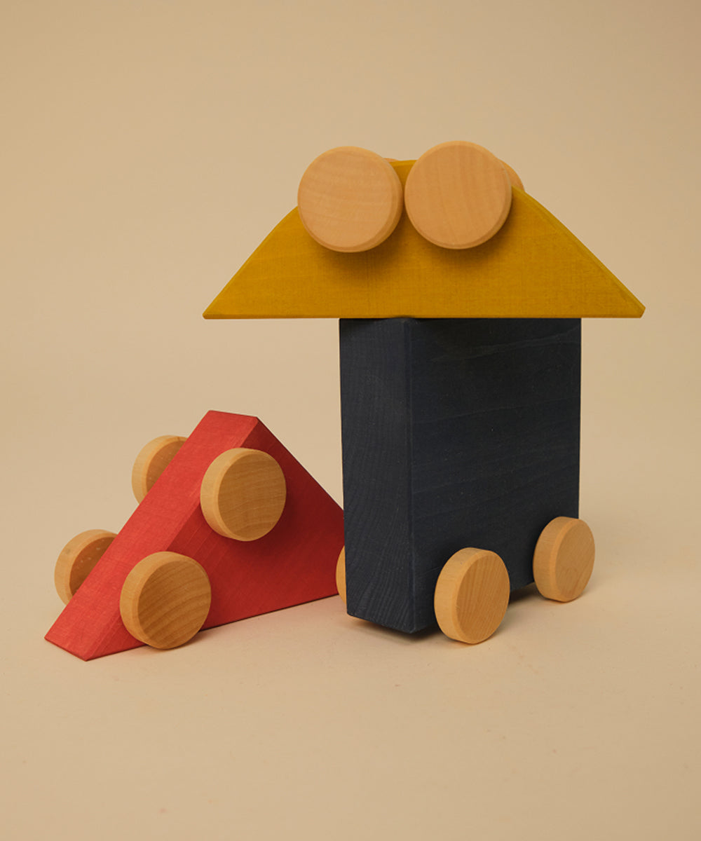 Le Vehicle Trio features two toy vehicles crafted from colorful wooden blocks with round wheels, displayed on a beige background.