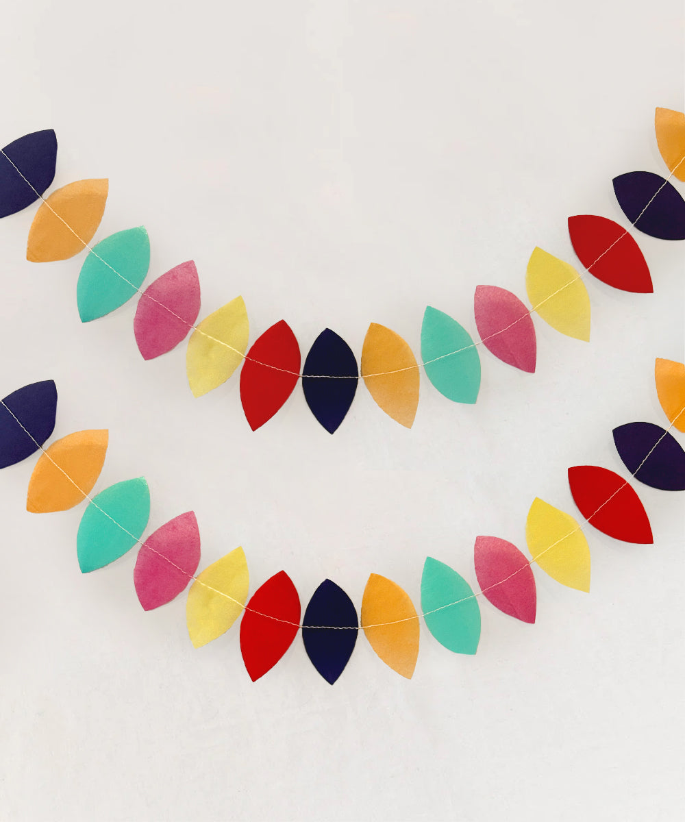 The Le Teardrop Garland features colorful leaf-shaped paper designs in blue, red, pink, yellow, and teal arranged in two diagonal lines against a light background.