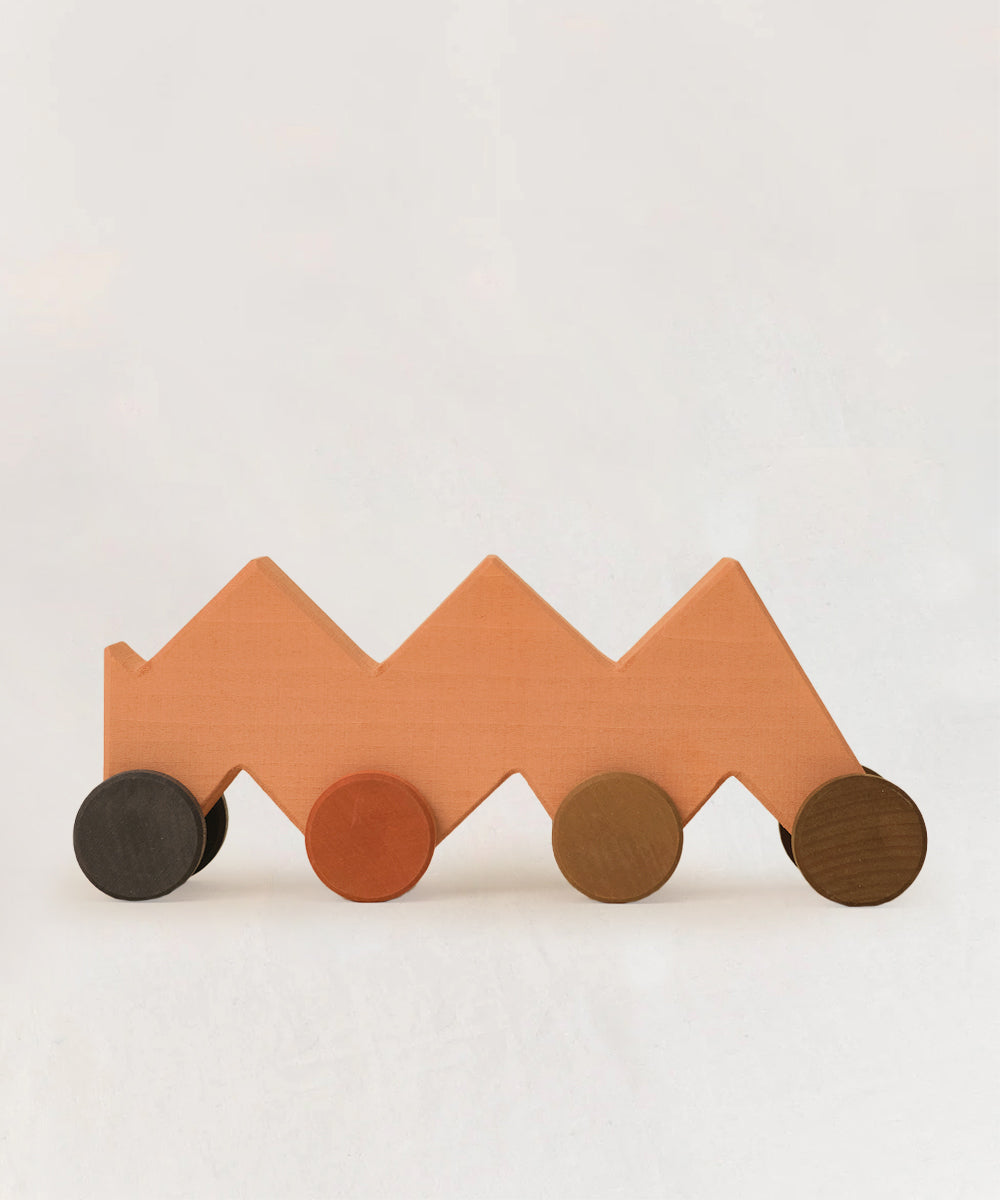 Le Zigzag Vehicle is a wooden toy car featuring four colorful round wheels, displayed on a plain white background.