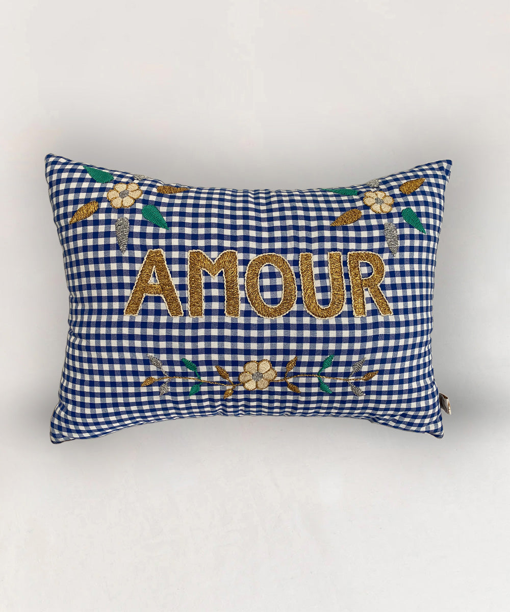 Le Embroidered Pillow - Gingham Amour: a rectangular blue and white gingham pillow with "AMOUR" and floral gold embroidery.