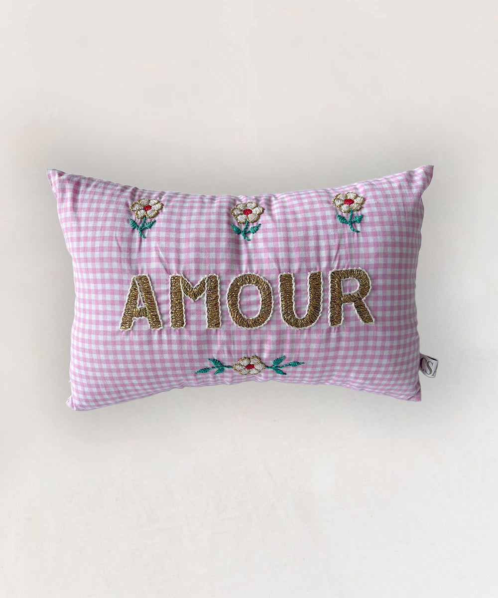 Le Mini Embroidered Pillow in pink gingham features "AMOUR" and floral embroidery on a white background.