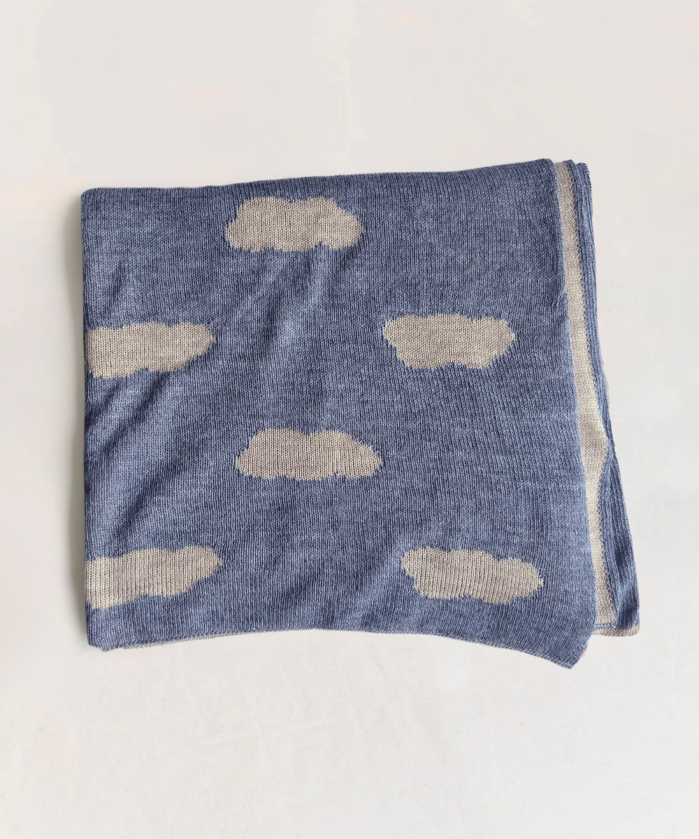 A folded Cloud Blanket features white cloud patterns on a light blue background.