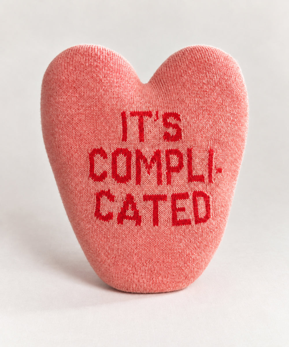 It’s Complicated Heart Pillow, a pink heart-shaped pillow with the text “IT’S COMPLICATED” in red.