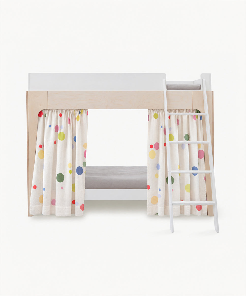 Perch Bunk/Loft Linen Curtains hanging from the lower level of a bunk bed, featuring a colorful polka dot pattern.