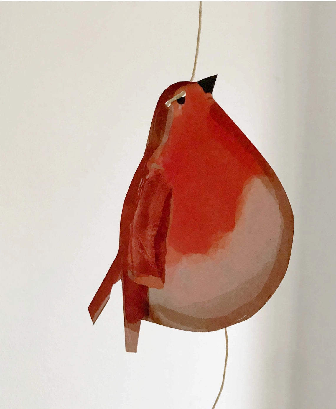 A "Le Garland - Robins" paper cutout of a plump red-breasted bird hangs by a string against a plain white background.