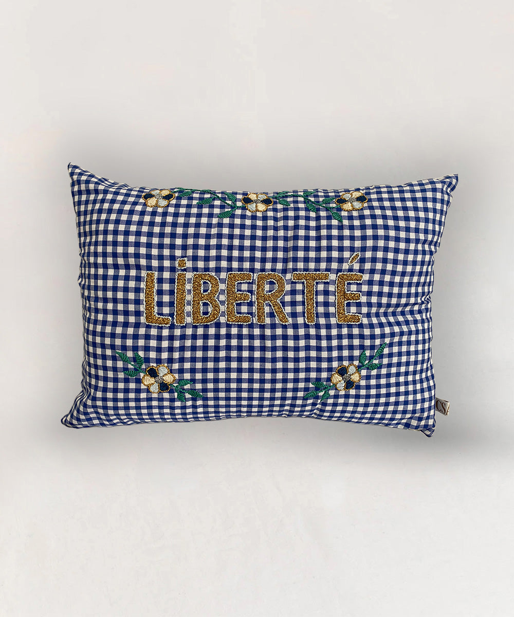 Le Embroidered Pillow - Gingham Liberté features blue and white checks with "LIBERTÉ" and yellow floral embroidery.