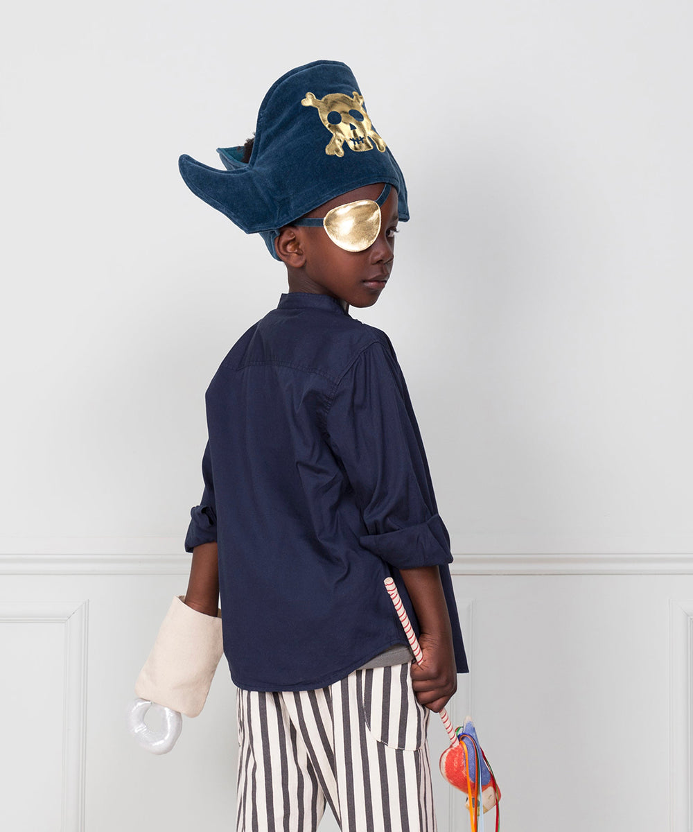 A child wearing the Pirate Costume with a blue hat, gold eye patch, and striped pants stands sideways holding toys.