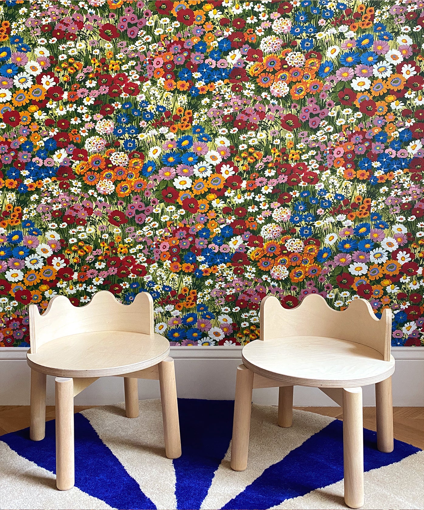 Two Moss Chairs facing floral wallpaper on a blue and white geometric patterned rug.