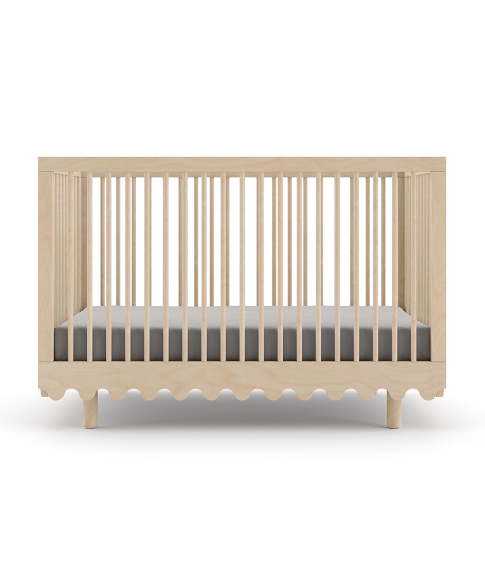 The Moss Crib features slatted sides, a grey mattress, and a distinctive wavy design along the bottom edge.