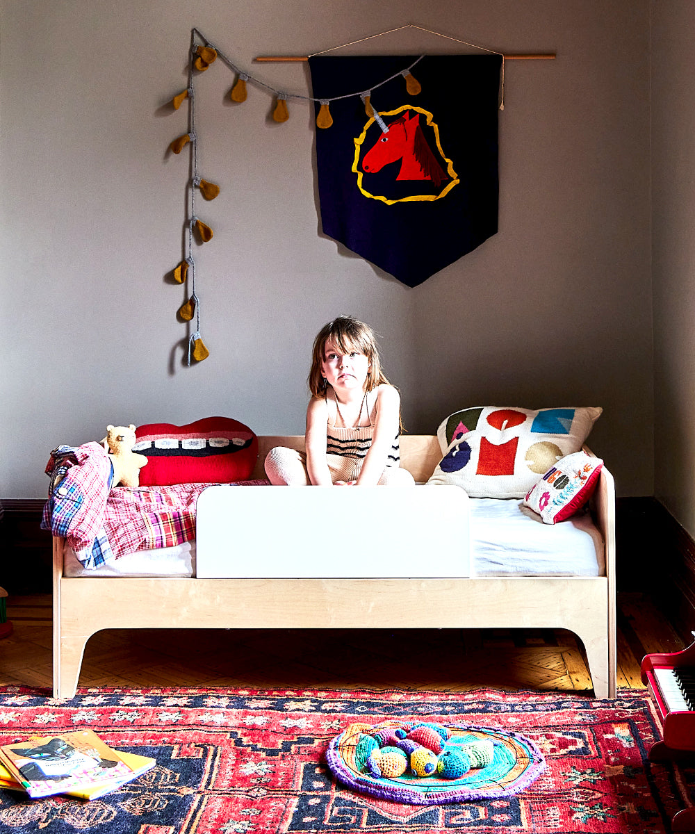 Child sits on bed in cozy room with Mouth Pillow - Braces, colorful decor, and scattered toys.