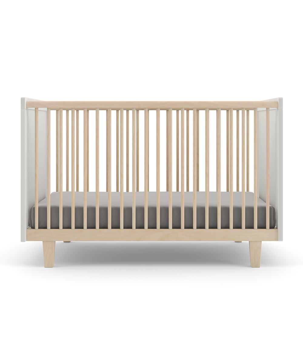 The Rhea Crib is a minimalist wooden baby crib featuring a gray mattress and vertical slats, viewed from the front.