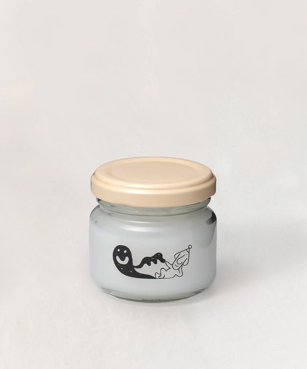A small glass jar labeled "Le Gentle Scissors" with a beige lid and a playful black and white face illustration on the front.