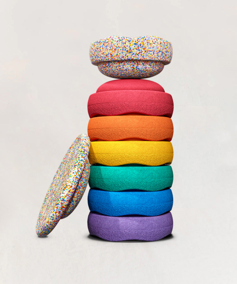 Le Stepping Stones - Complete Set: A stack of colorful, donut-shaped cushions in rainbow order with confetti-patterned tops and bottoms.