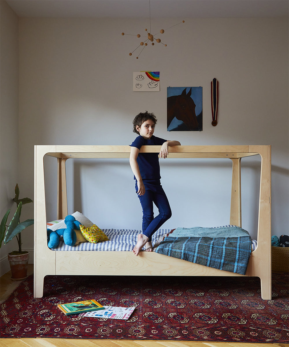 photo of Nest Bed in canopy configuration with boy standing on edge of bed.  Simple, nicely lit room
