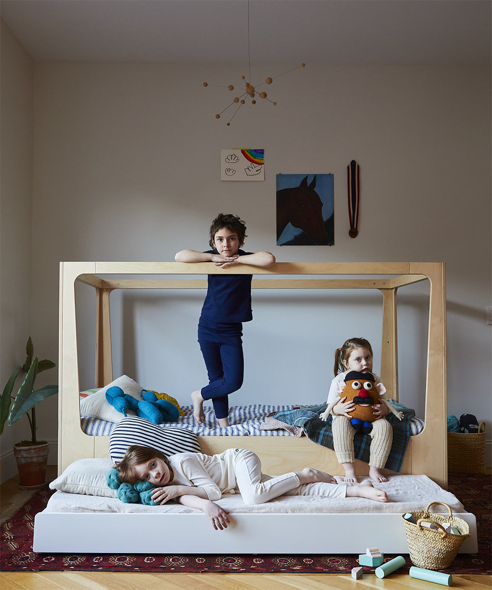 photo of Nest Bed in canopy configuration with Perch trundle bed.  Three kids lounging on the bed and trundle.